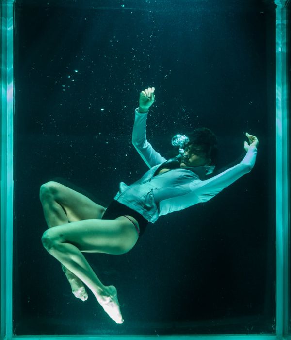 Person in a dynamic yet fluid pose in a minimalist studio.